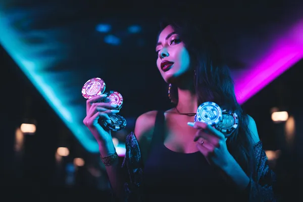 A young woman relaxing with her phone while dynamic casino elements float around her, illustrating the smooth mobile experience offered by the ZBZBET app.