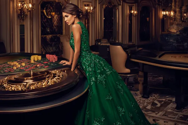 A woman in a luxurious green gown next to an ornate roulette wheel, capturing the upscale casino mood of ZBZBET.